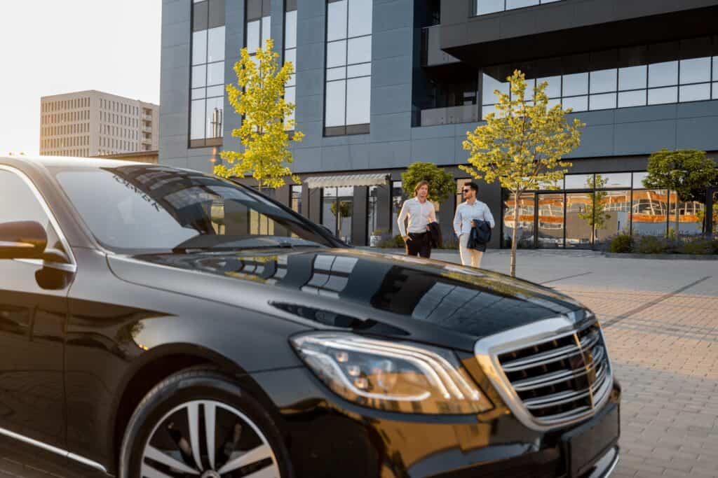 Mitä eroa on taksilla ja tilausajopalvelulla? 6 Kaksi liikemiestä kävelee kohti tilausajopalvelun kautta tilaamaansa kuljetusta.